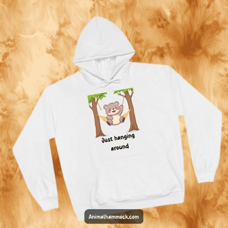 Funny chubby bear cub gleefully dangling from a hammock strung between two trees, featured on this warm hoodie.
